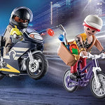 Two toy figures on motorcycles with a cityscape background