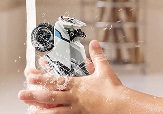 Hand holding a transparent bottle with a black and white lid, filled with water droplets.