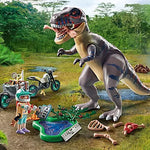 Toy dinosaur and figures in a jungle setting with trees and grass.