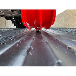 Close-up of a red vehicle tire on a wet road with a blurred background