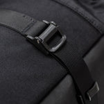 Close-up of a black backpack strap with buckle on a dark background