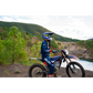 Person on a dirt bike in a scenic outdoor setting with mountains and trees.